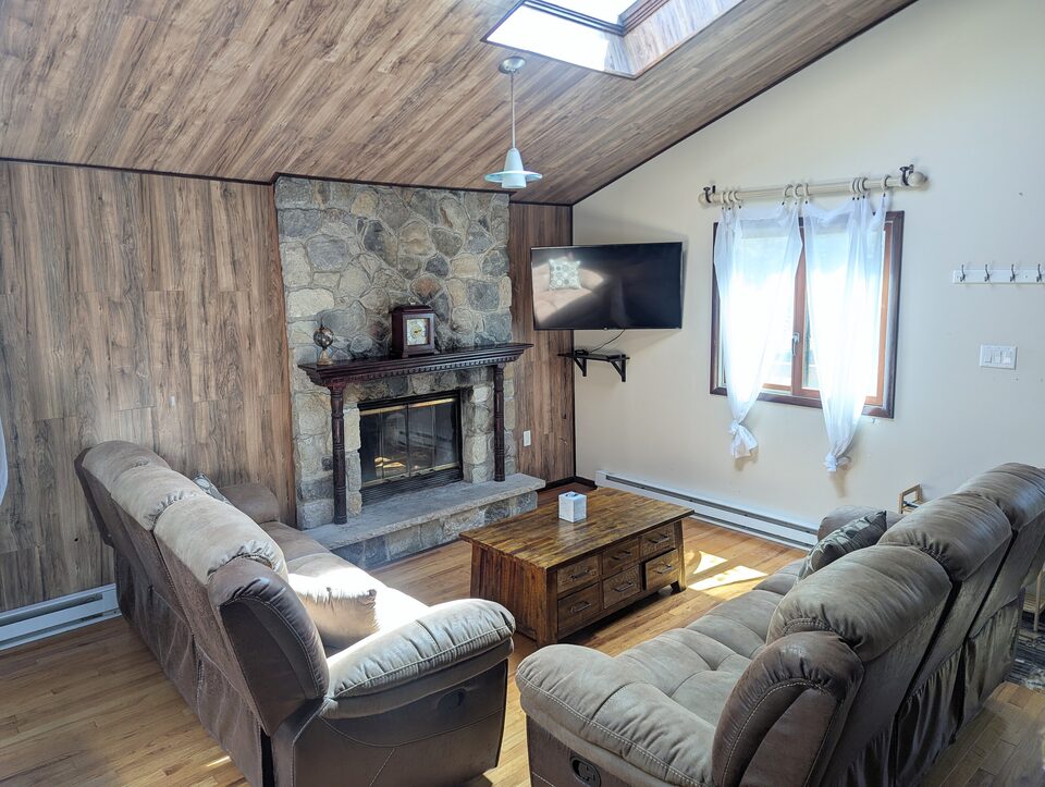 Close view of the stone fireplace and hearth with a coffee table and two recliner armchairs